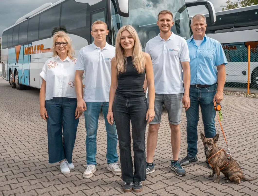 Die Familie Müller mit Bürohund vor einem Reisebus