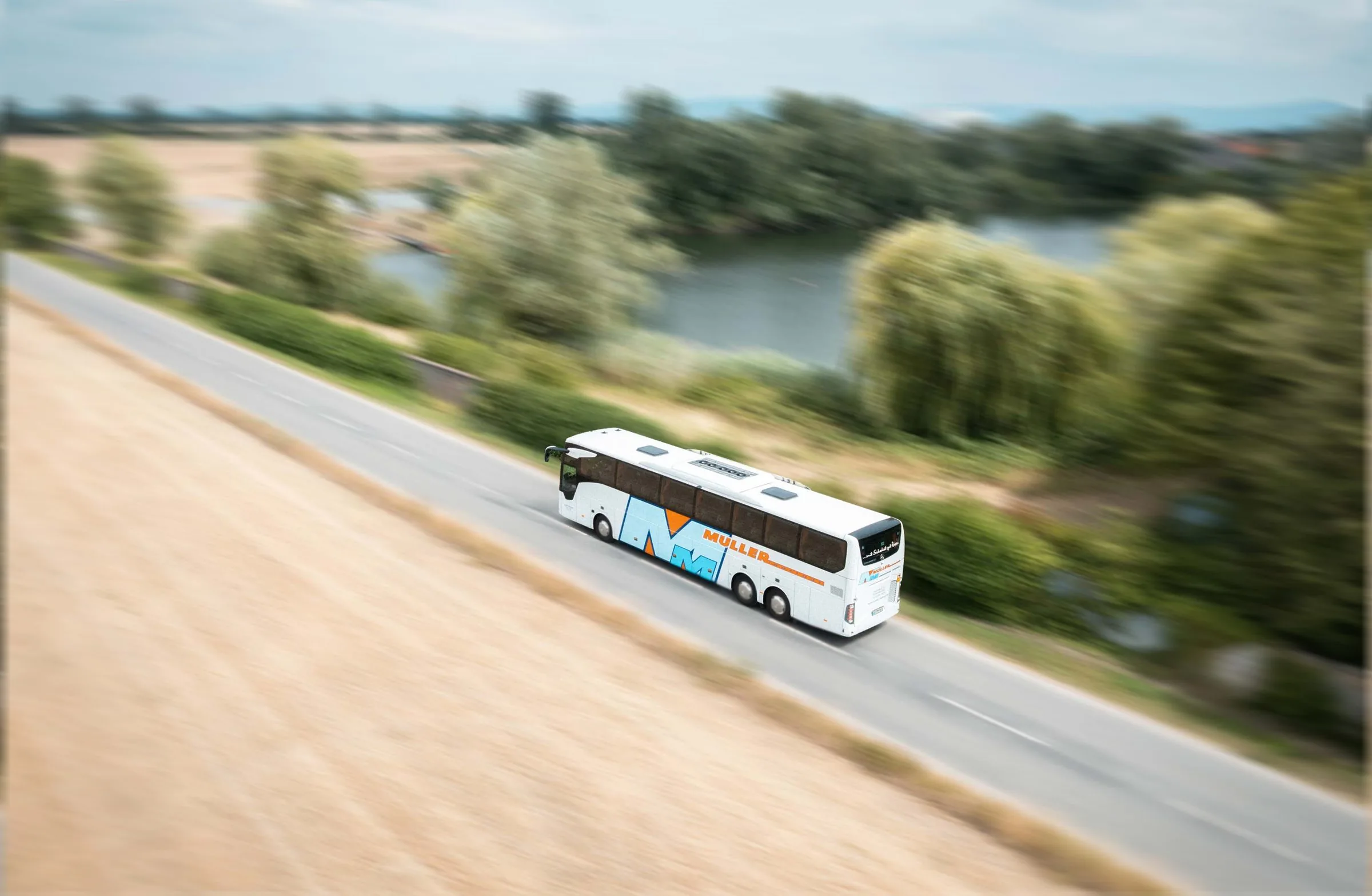 Reisebus von MÜLLER Riedstadt unterwegs am Wasser – aus der Luft aufgenommen