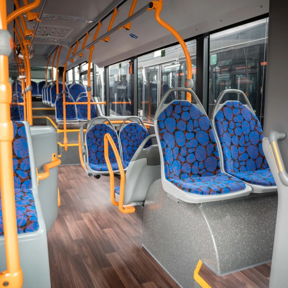 Innenraum eines Linienbusses mit blauen Sitzen und orangen Haltestangen
